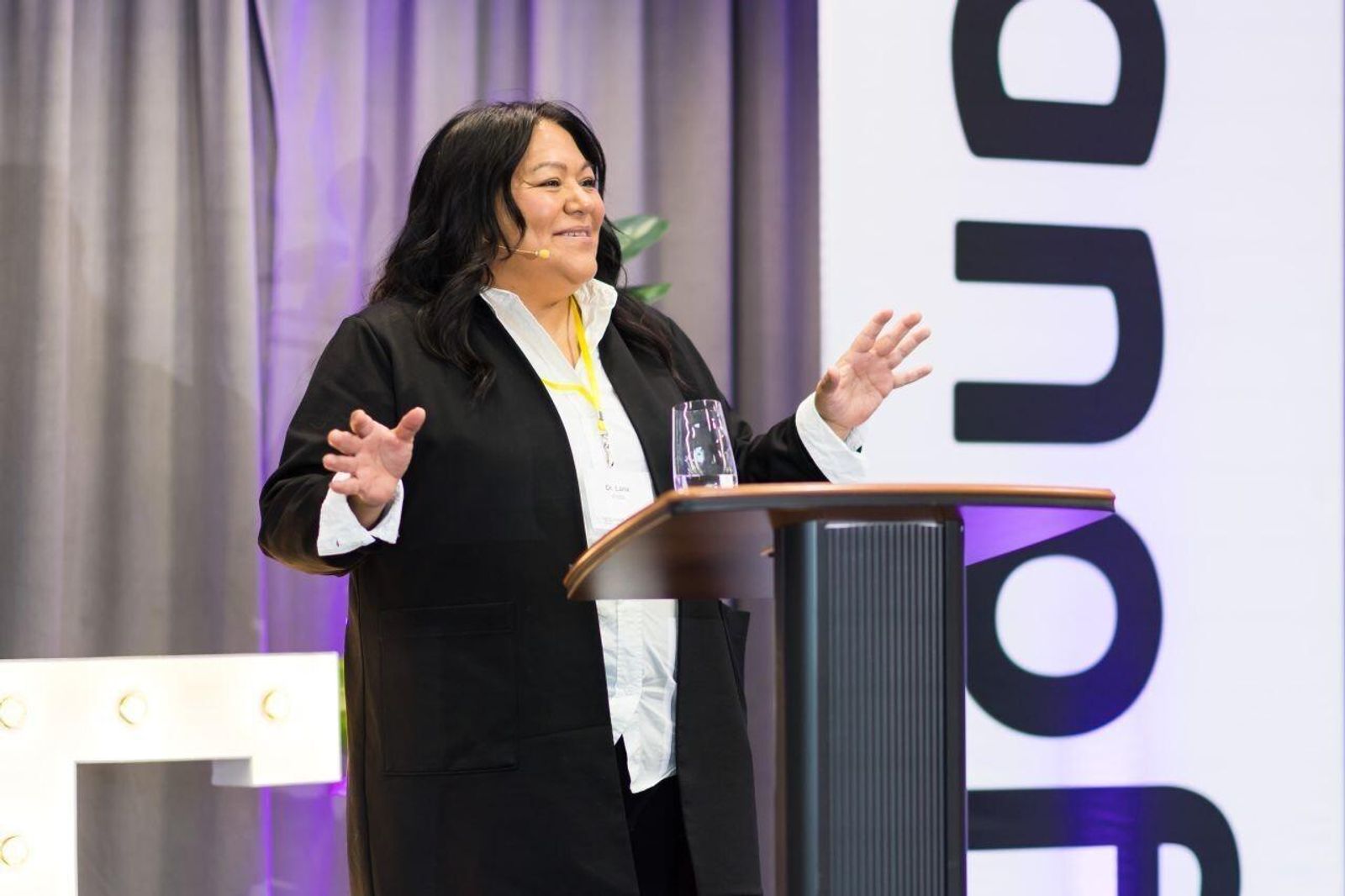 Dr Lana Potts Speaking behind a lectern on stage at TIE Summit