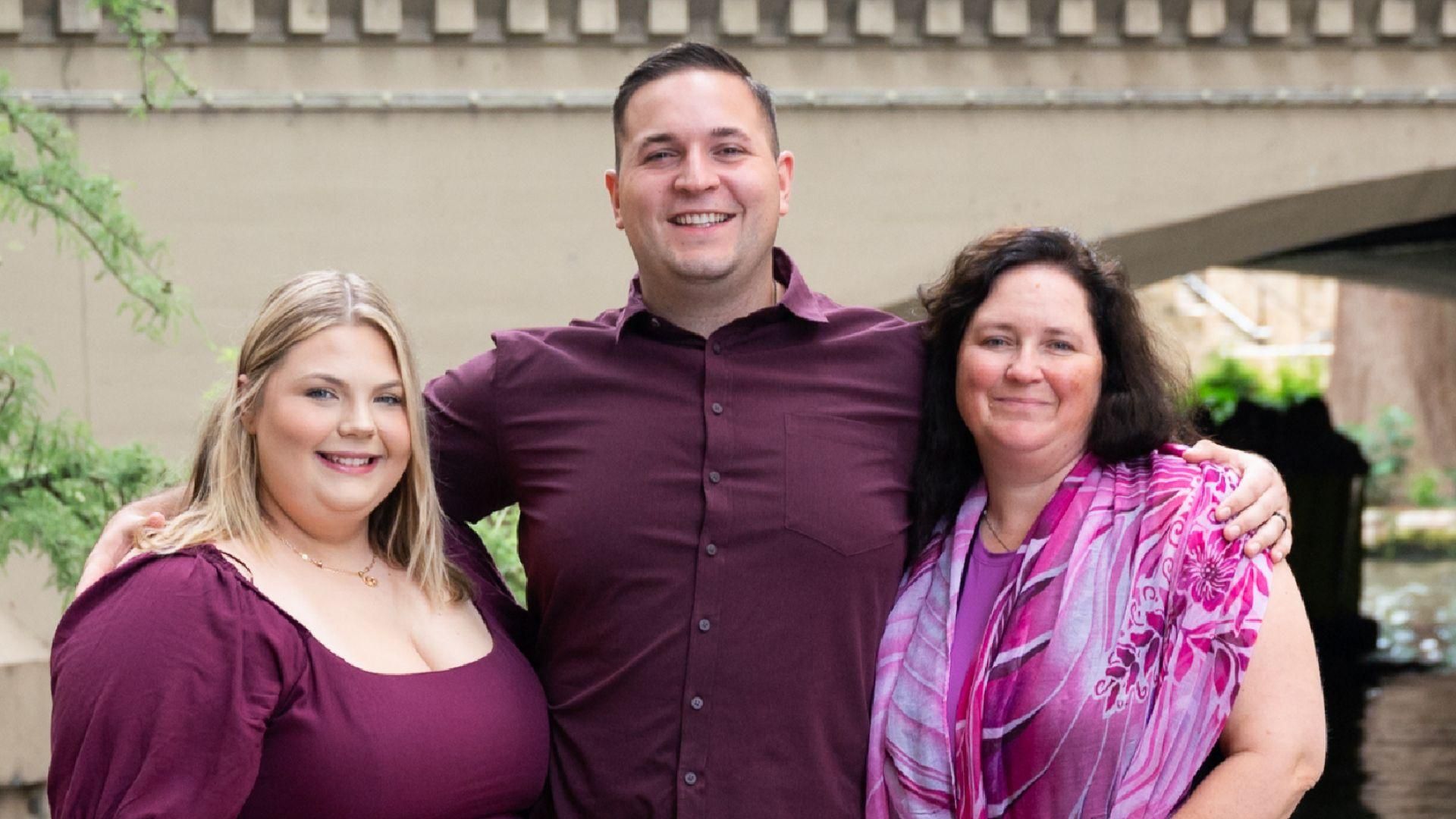 John is standing with his wife and mother