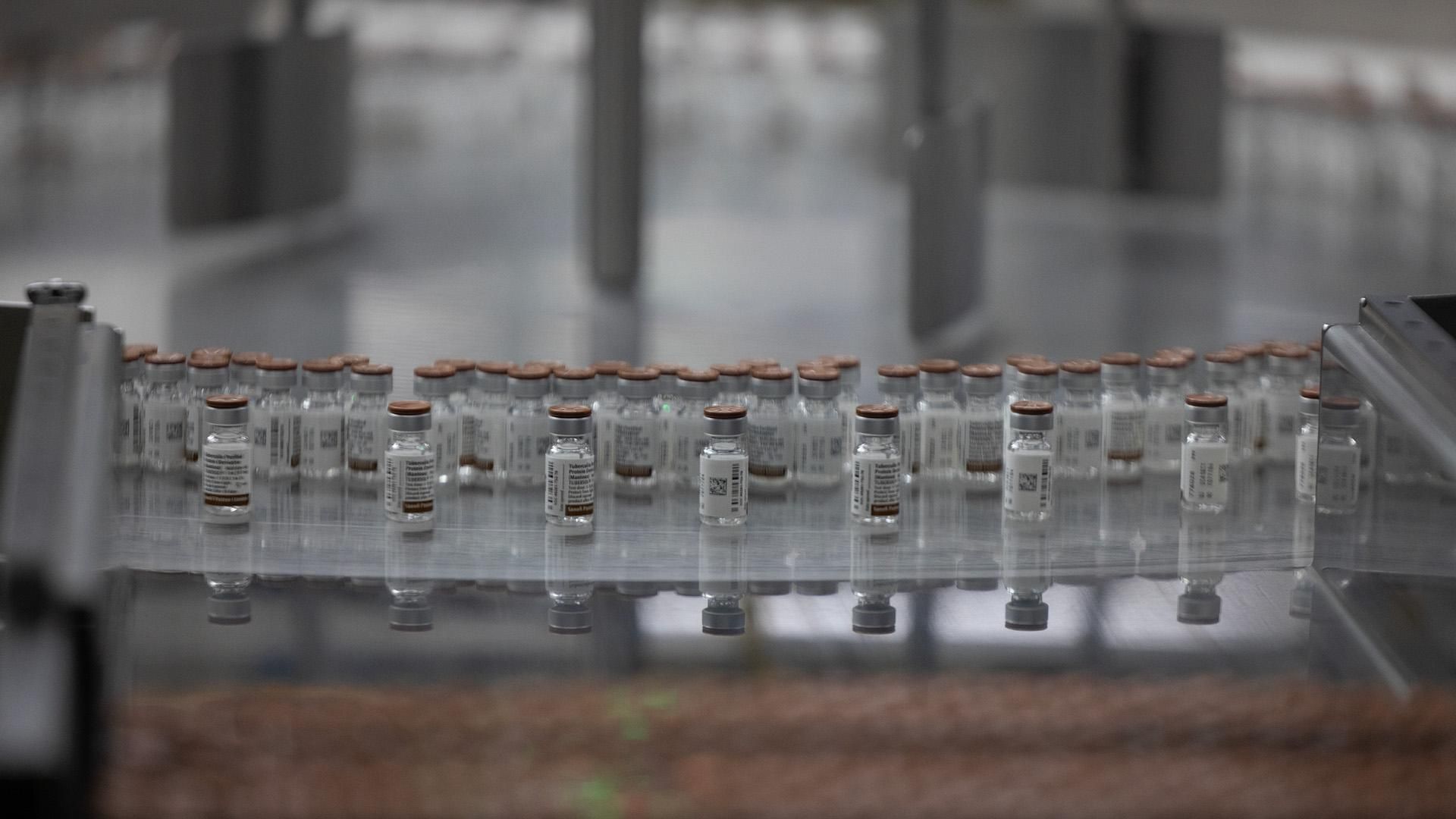 A close up of small labelled glass vials with brown caps on a labelling line