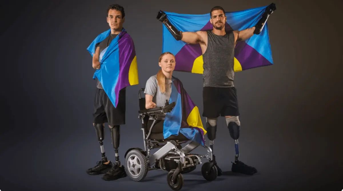 Caption: Théo Curin, Ellie Challis and Davide Morana flying the Meningitis Flag