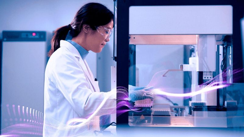 Shuang Yang, Scientist, China, working in a laboratory with automated scientific equipment, wearing a white lab coat, facing away from the camera.