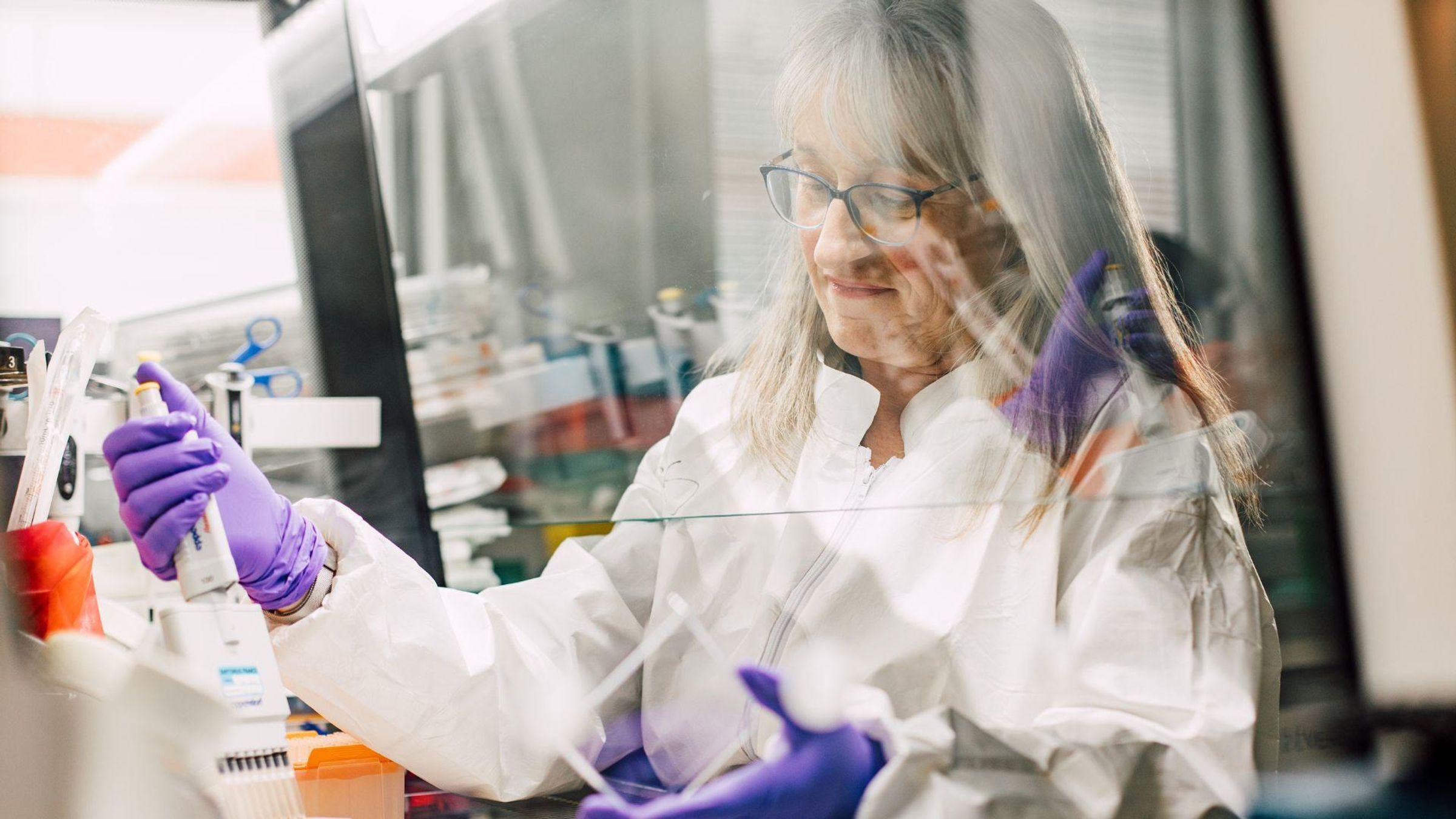 Christine Dureuil-Sizaire, Principal Scientist at Sanofi, wearing a lab coat and gloves while conducting research work in a laboratory at the Vitry-sur-Seine facility in France