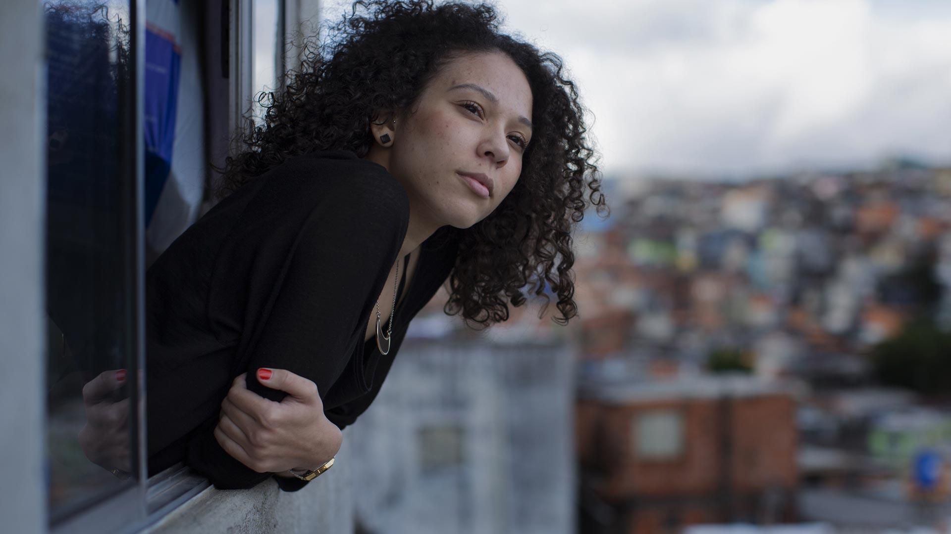 Une femme penchée à la fenêtre de son appartement au Brésil