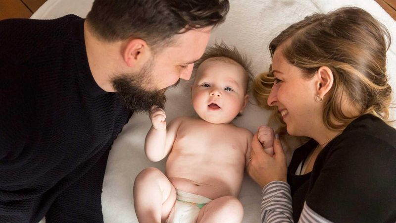 Parents holding a baby in a living room