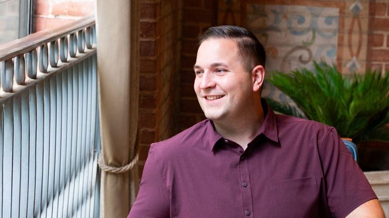 John, sitting in a chair and smiling